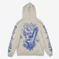 The Cherub Harp Hoody by Electric Picnic is a beige hoodie with blue designs of a cherub playing a lyre, surrounded by flowers and birds. Electric Picnic features above the cherub, with blue floral and bird sleeve patterns.