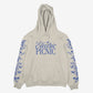 The Cherub Harp Hoody by Electric Picnic is a light beige hoodie featuring large blue script Electric Picnic on the front and blue floral designs down both sleeves.