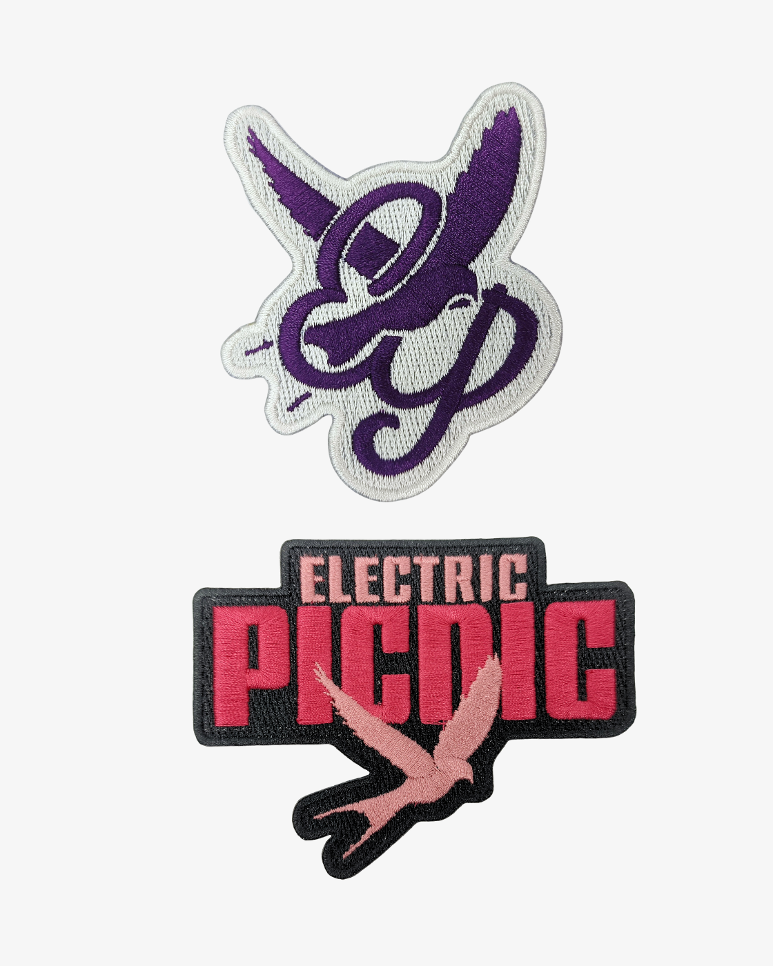 The EP 2026 Click & Collect Patch Set includes two embroidered patches: the top patch features a purple bird with stylized wings and letters, while the bottom patch displays “ELECTRIC PICNIC” in bold letters with a pink bird beneath, both set against a white background.