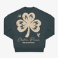 The EP 2026 Click & Collect "Click & Collect Vintage Clover Crewneck 2" is a dark sweatshirt featuring a large, distressed-style cream shamrock, two small birds, and the text “Electric Picnic MUSIC AND ARTS FESTIVAL” printed on the back.