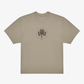 The Click & Collect Vintage Clover Oversized T-Shirt by EP 2026 Click & Collect features a beige short-sleeve design with a black four-leaf clover graphic and circular text on the chest, along with a small curved line or signature beneath the clover.